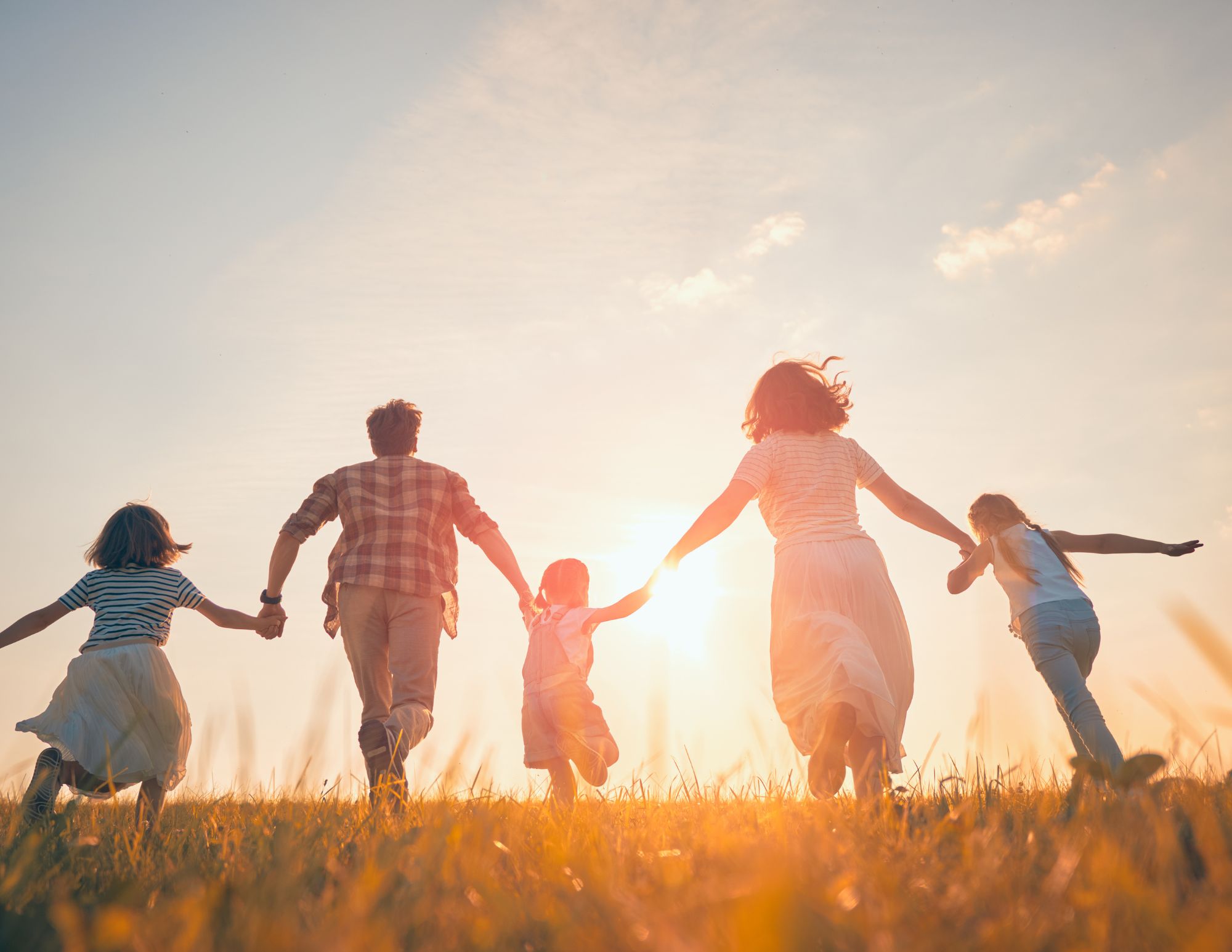 Family running together joyfully in a sunny field